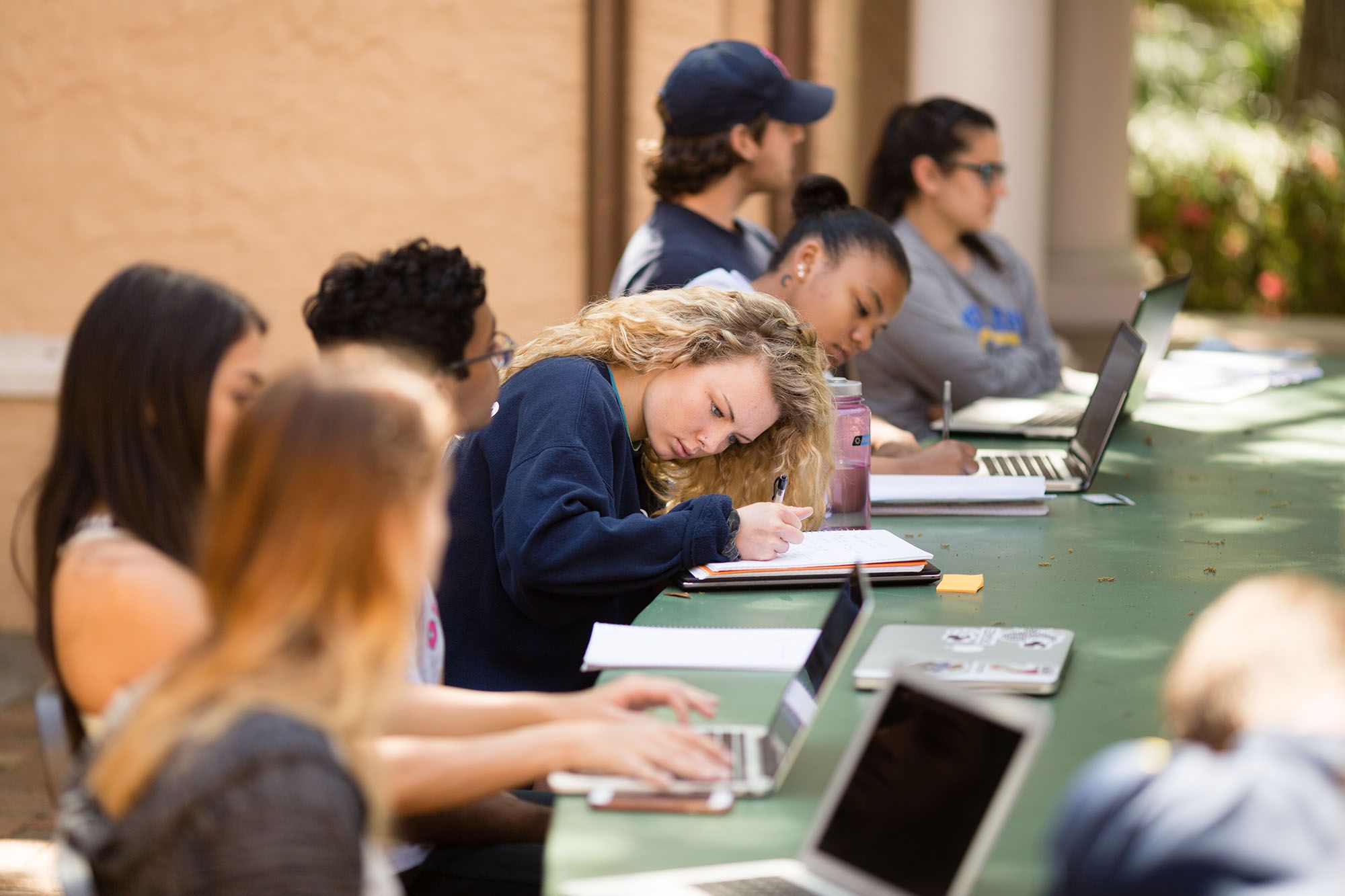 A student takes notes in an international relations course in Rollins’ outdoor classroom.