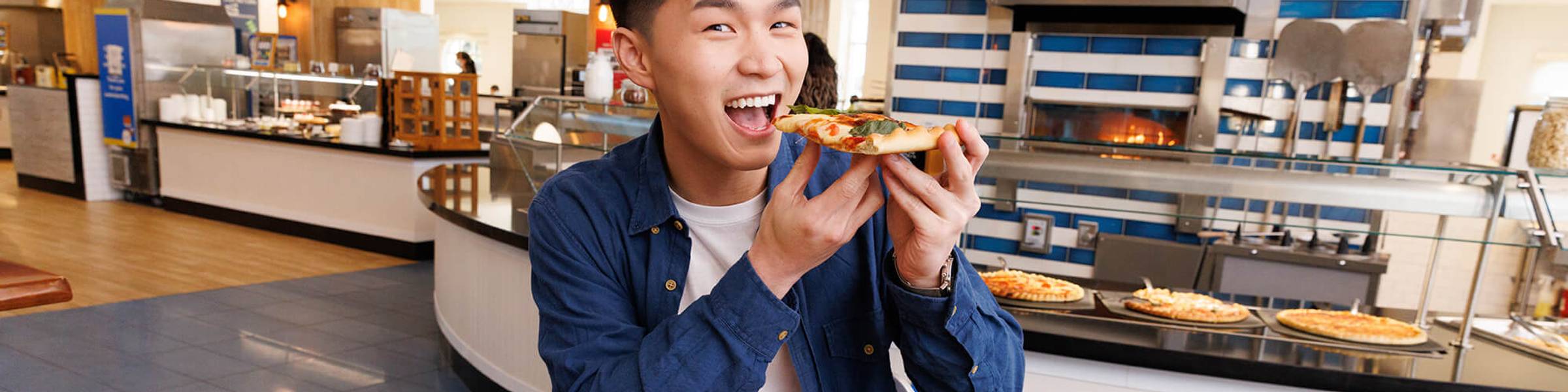 A Rollins student takes a bite of pizza while in the main campus dining hall.