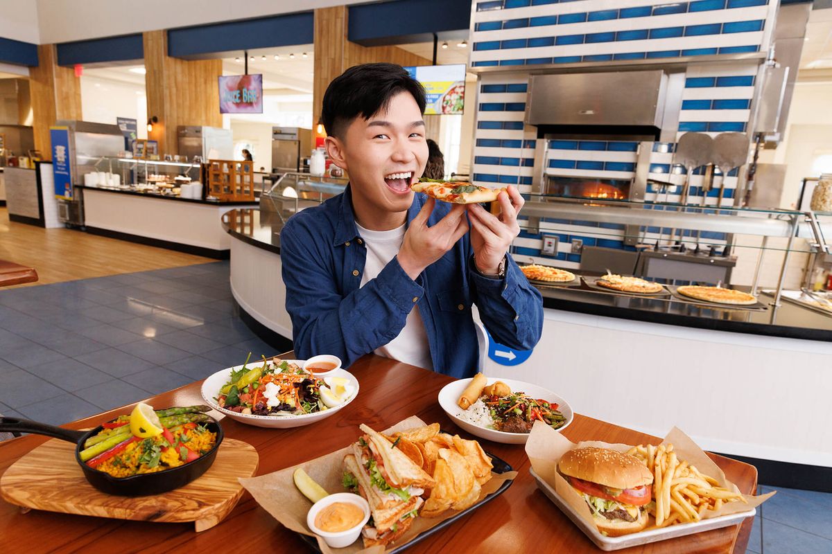 A student poses for a picture surrounded by plates of food at Rollins’ main dining hall.