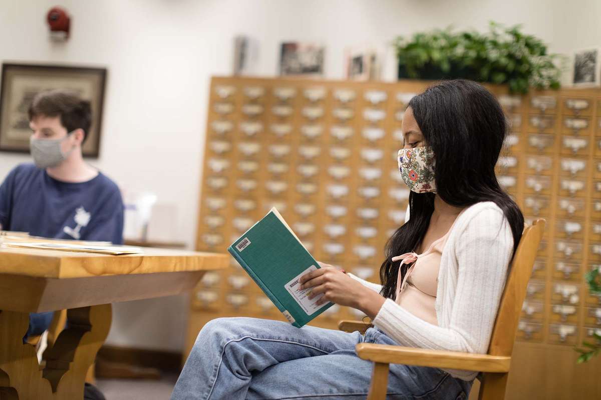 Masked student reads a book