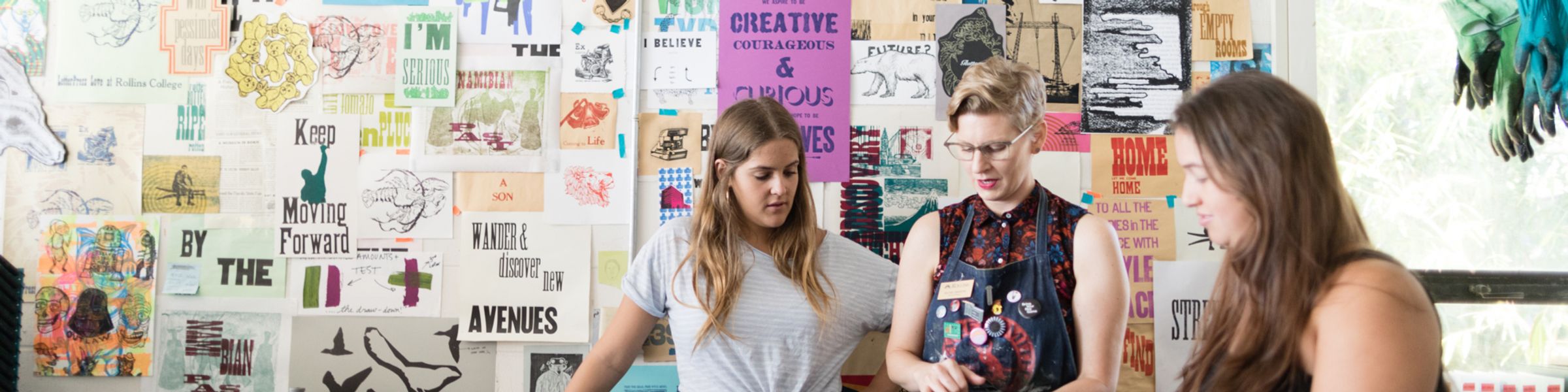 A professor and two students reviewing a print in Studio Art class.