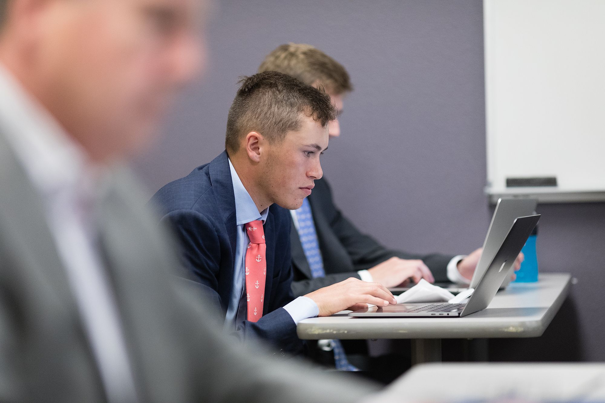 A student takes notes on his laptop during a business class.