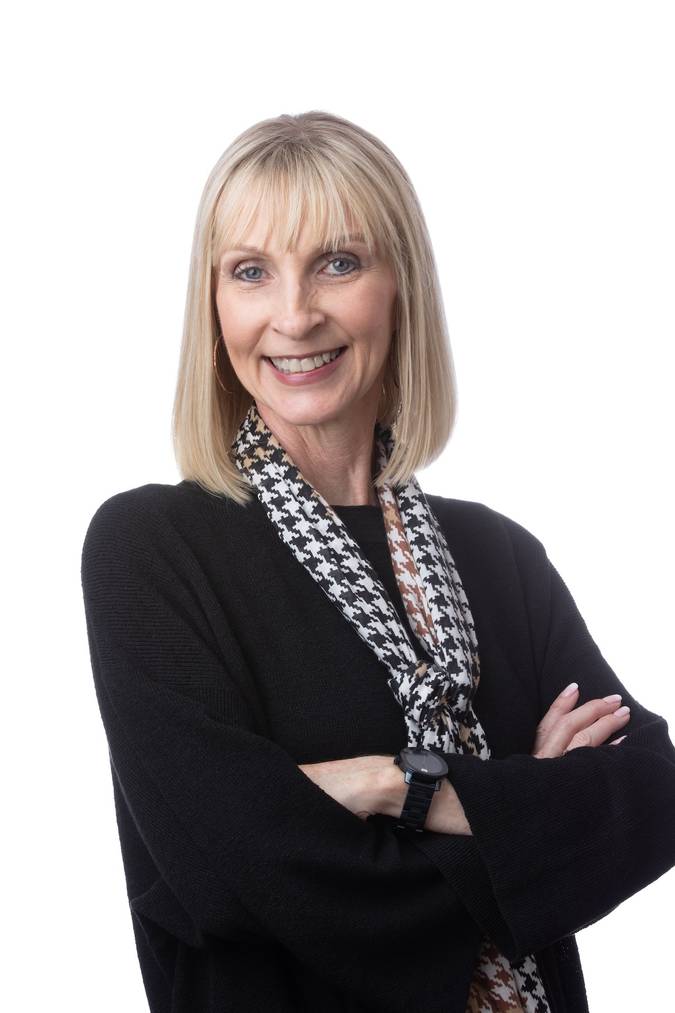 Smiling Pennie Parker posing confidently with folded arms against white background