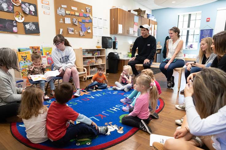 A group of Rollins students read with a group of preschool children.