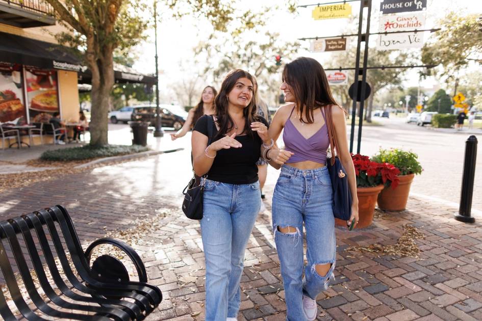 A pair of students walk down the sidewalk in Winter Park, Florida.