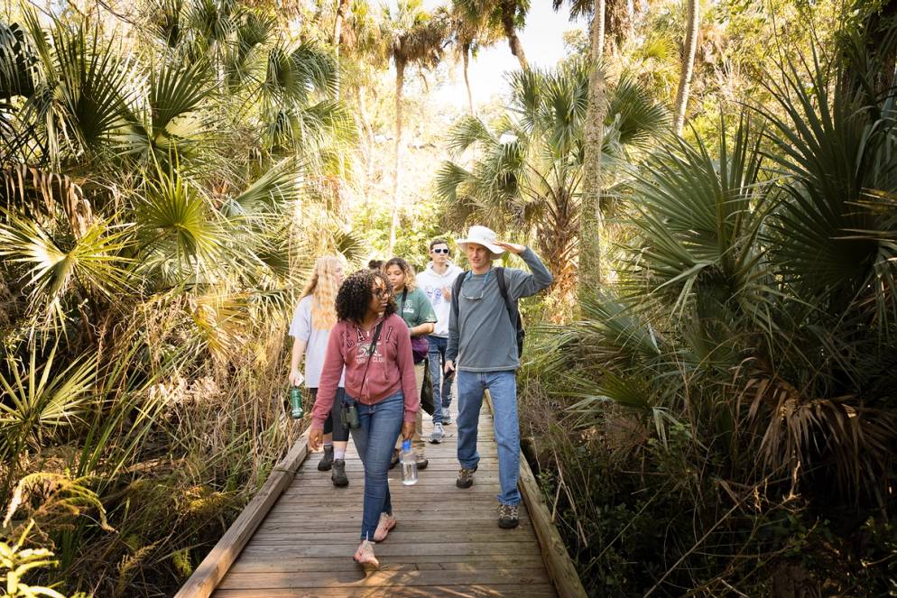 A professor and students walk a hiking trail.