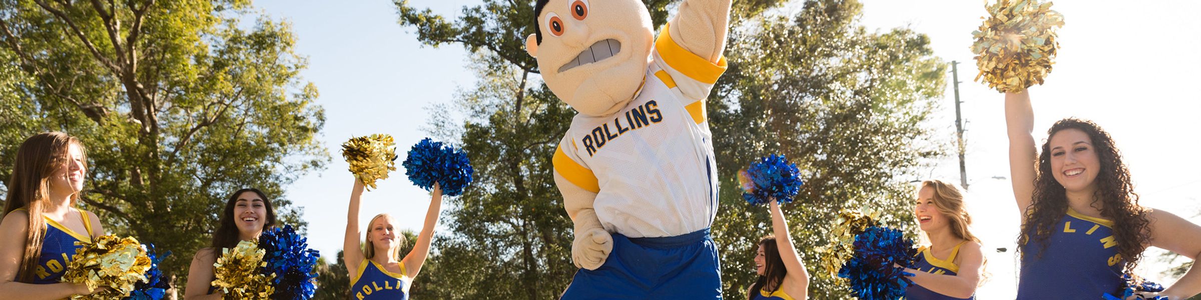 Rollins' mascot, Tommy Tar, jumps surrounded by the Rollins dance team waving pom-poms.