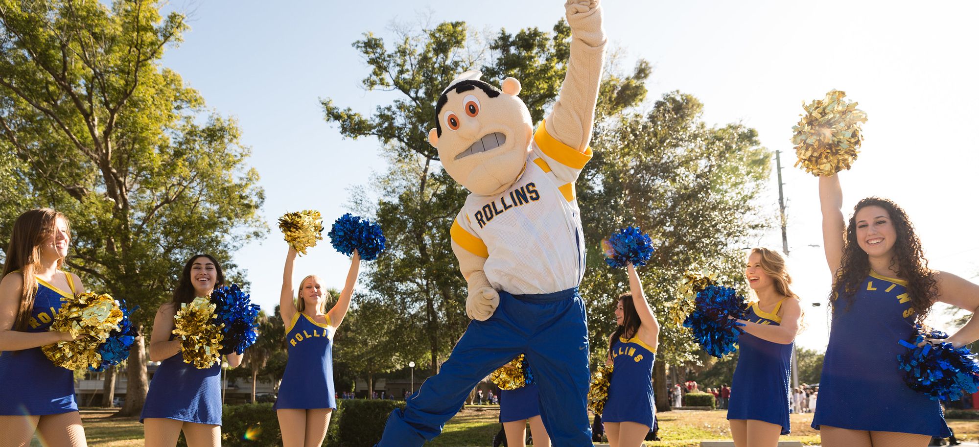 Rollins' mascot, Tommy Tar, jumps surrounded by the Rollins dance team waving pom-poms.