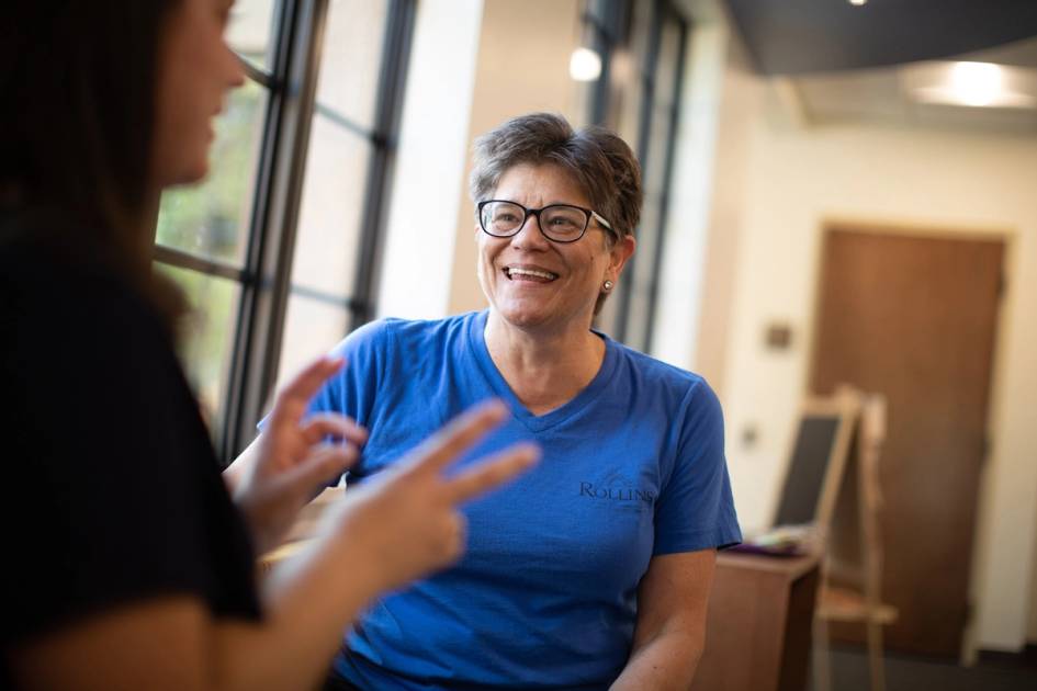 A faculty advisor smiles as she listens to a student.