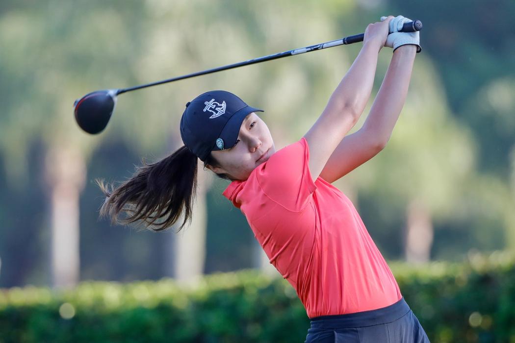 A female golfer hits the ball off the tee.