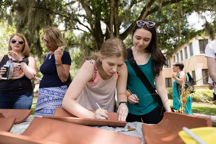 Rollins students sign roof tiles for the construction of Kathleen W. Rollins Hall.