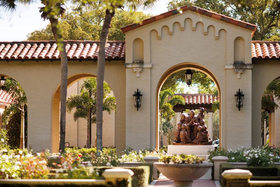 archway on campus looking through rose garden to Mister Rogers statue