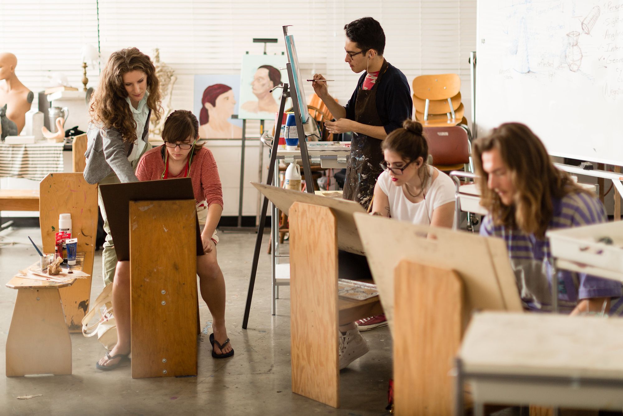 A professor instructs a student during a painting class.