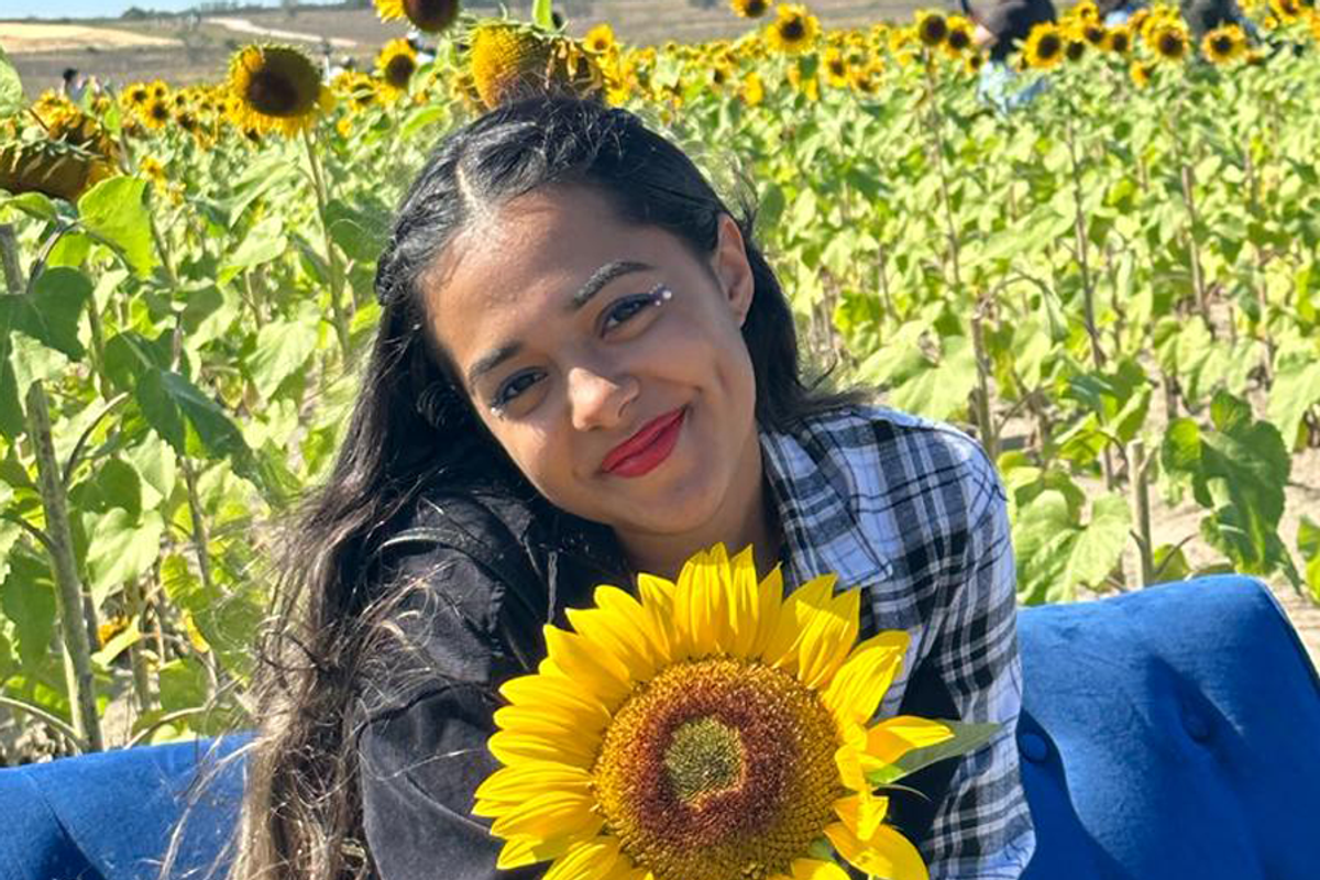 Rollins student Denathany Cerpa poses in a field of sunflowers.