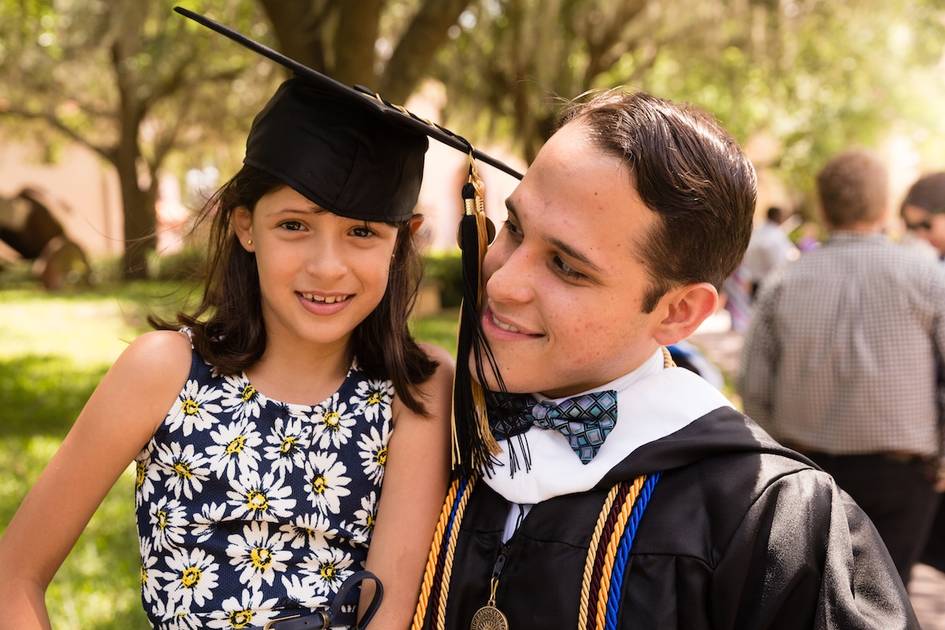 A Rollins graduate poses with his child at commencement.