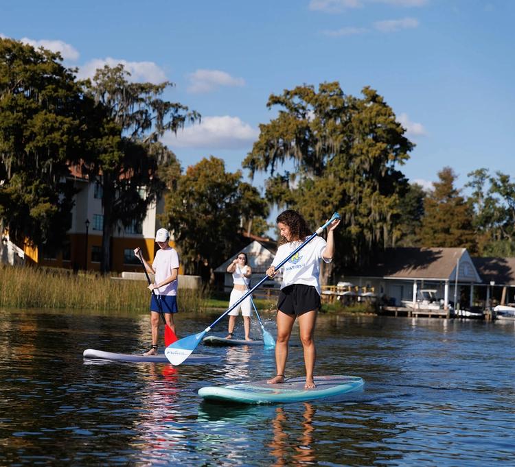 Rollins campus, on Lake Virginia, students are paddle boarding in front of the boat house.