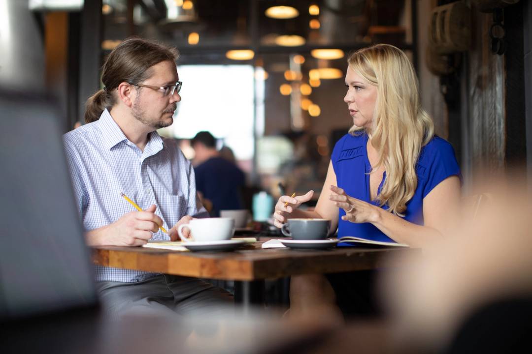 An adult college student meets one on one with a professor in a cafe.