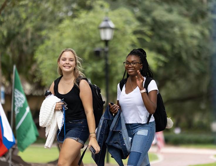 Two Rollins College students walk across campus together. 