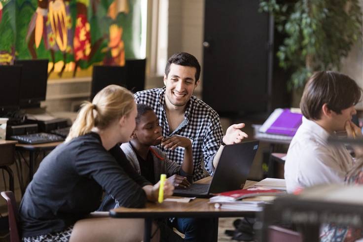 A pair of college students teach a fourth grader to code.