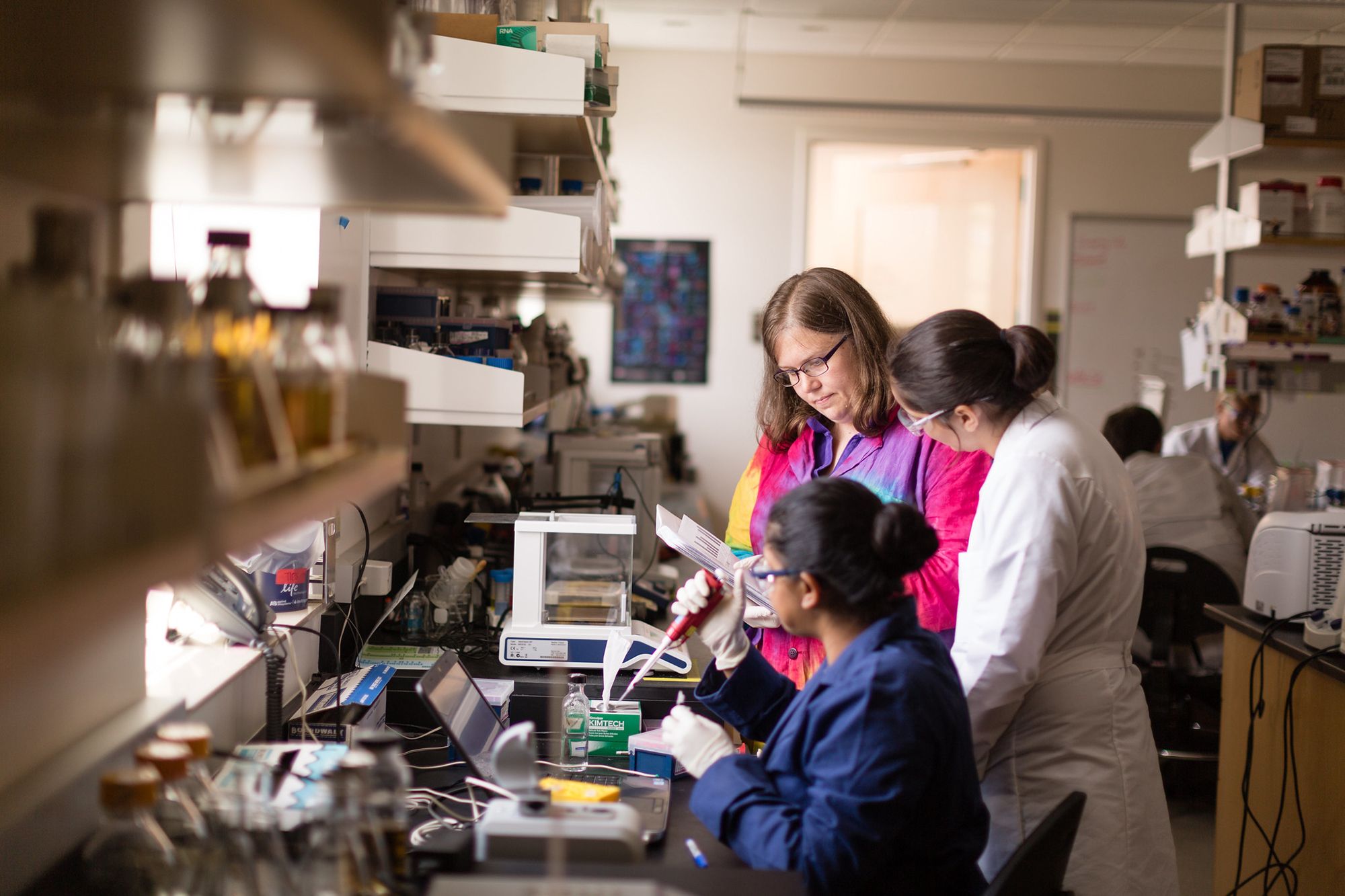 A professor and two students conduct chemistry research.