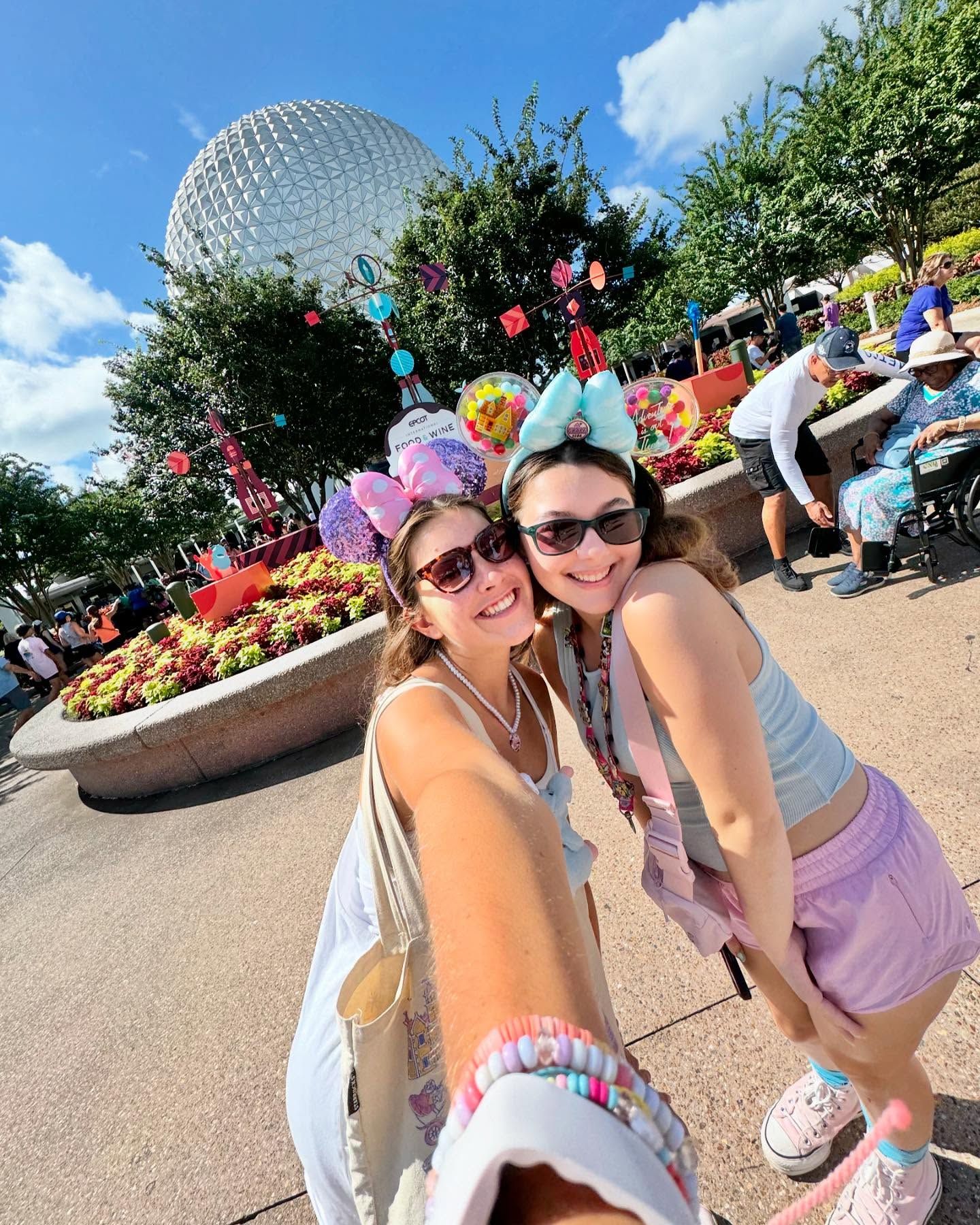 Two students wearing Minnie Mouse Ears in front of the EPCOT's Spaceship Earth ride.