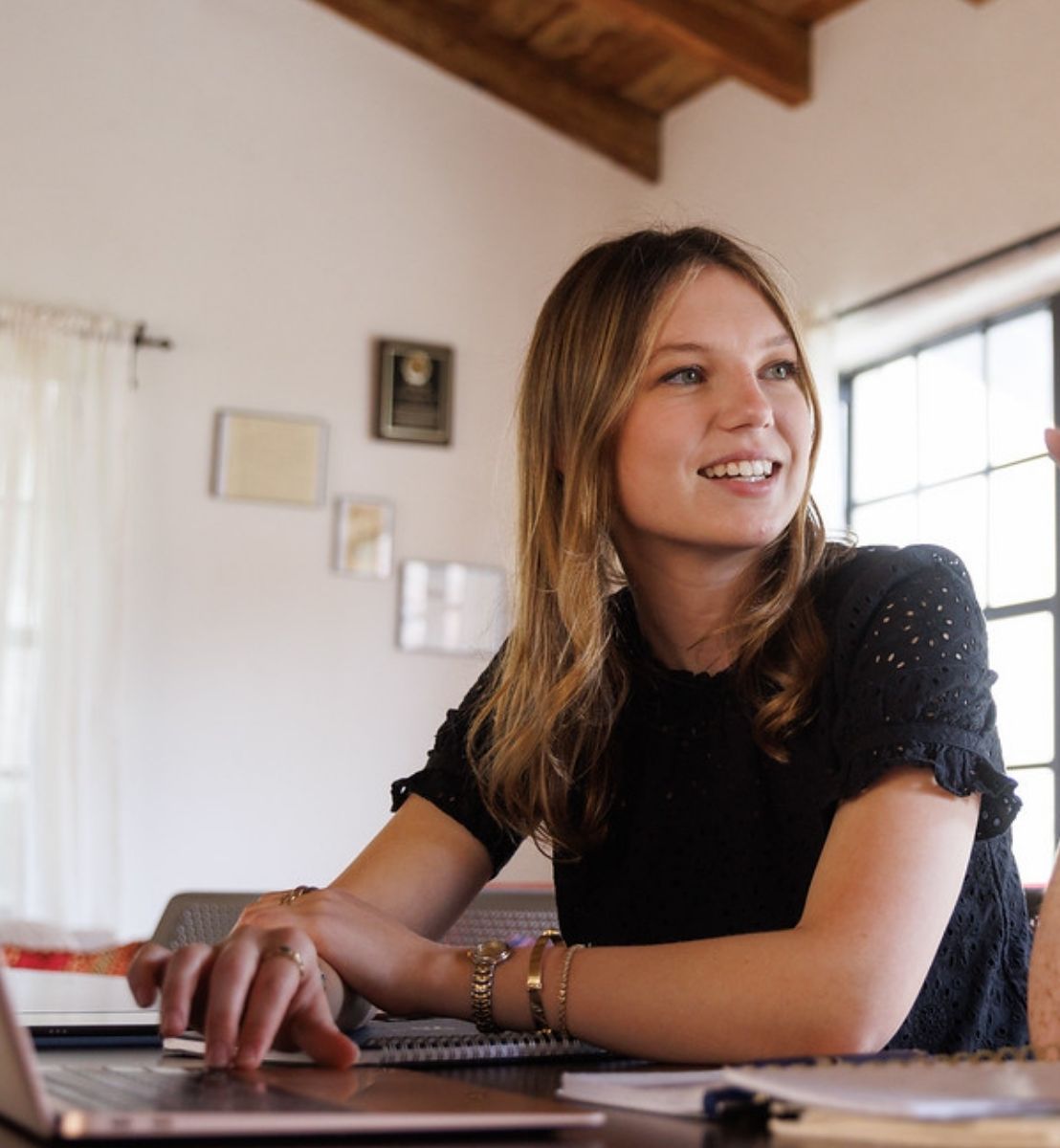 Capri in cap and graduation robe with cords and ribbons, outside on Rollins campus.