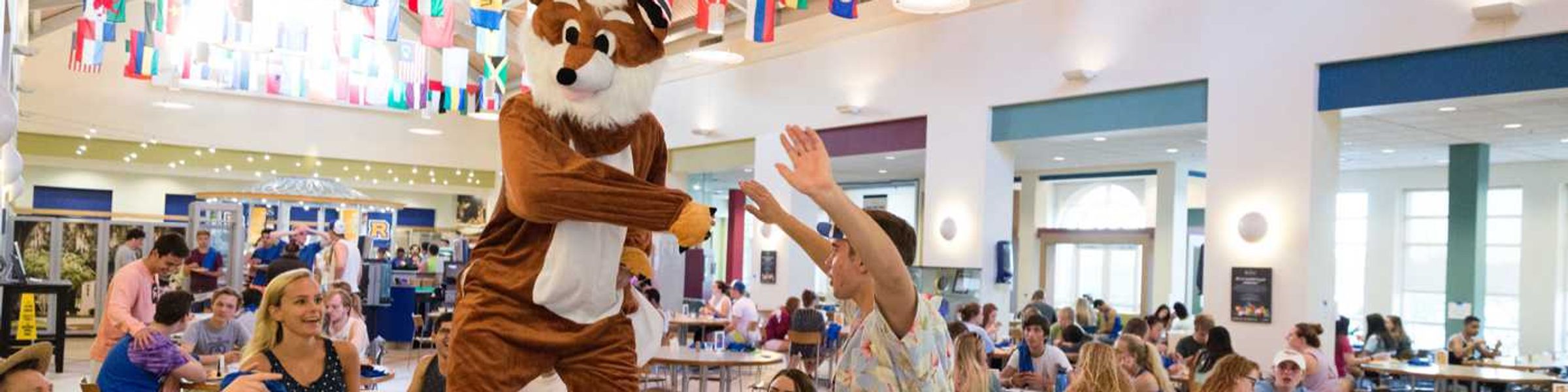 A fox mascot dances on a table in the Marketplace.