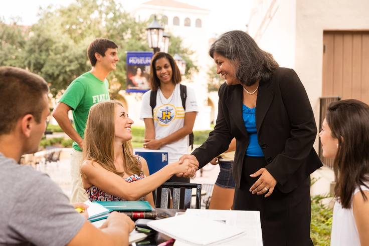 Vice president of student affairs greeting students.