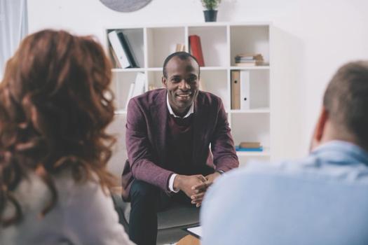 A clinical mental health counseling professor talks with two students.