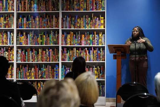 A student stands at a podium and delivers a talk about an art installation.