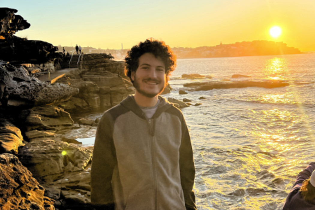 Student in front of a sunset over an Australian coast