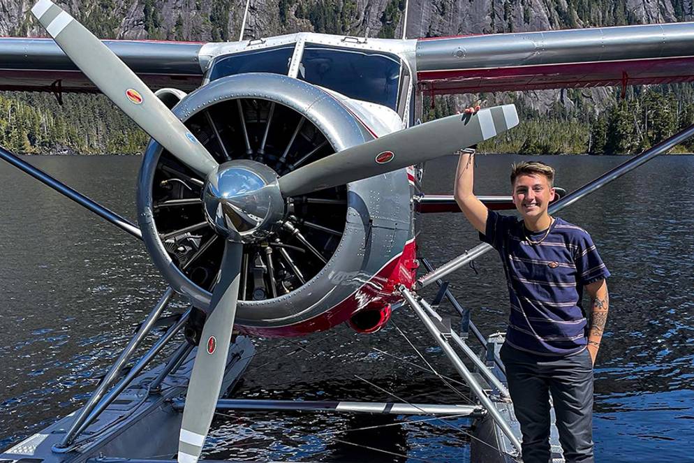 Mary Scott stands in front of a seaplane on the water.