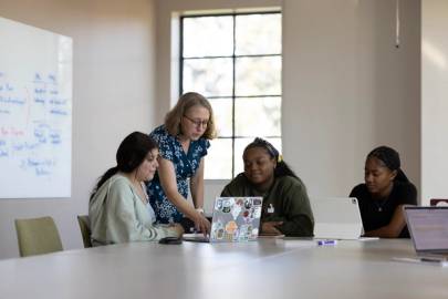 Three students and a professor collaborating in a classroom.