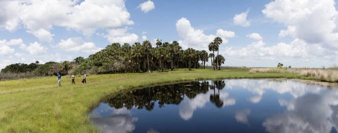 Students walking through the grasslands near a lake.