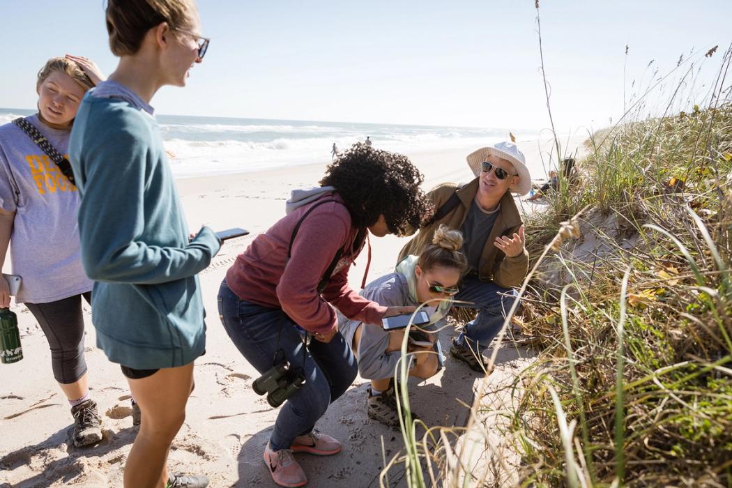 A professor lectures to a group of students during a class at a beach in Florida.