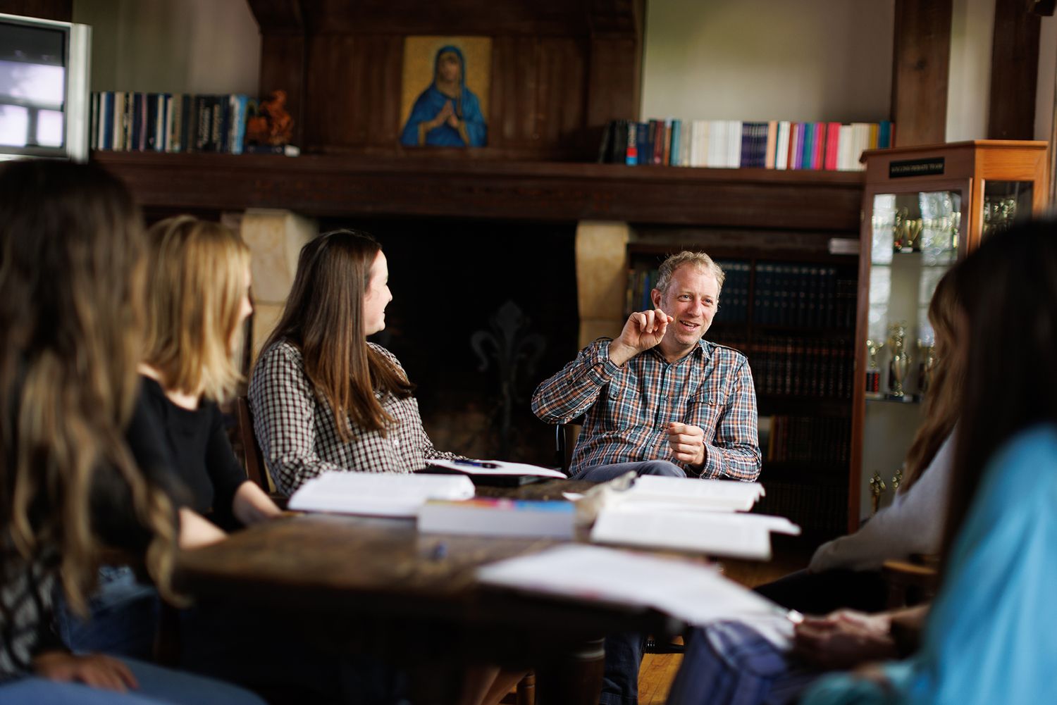 A professor leads a class discussion with a small group of students gathered around a table.