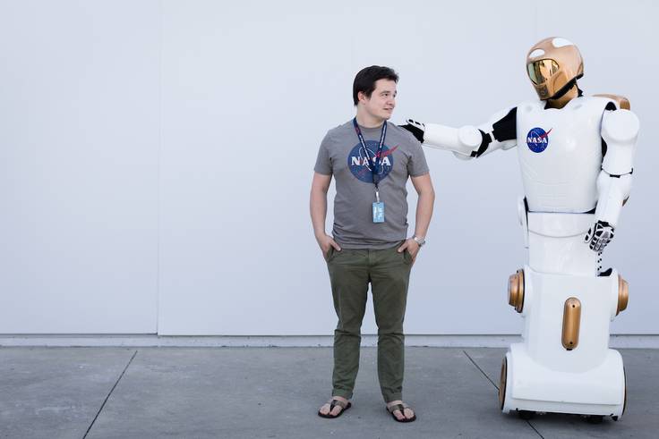 Rollins student, Michael Gutenshon, stands with a robot at Kennedy Space Center.