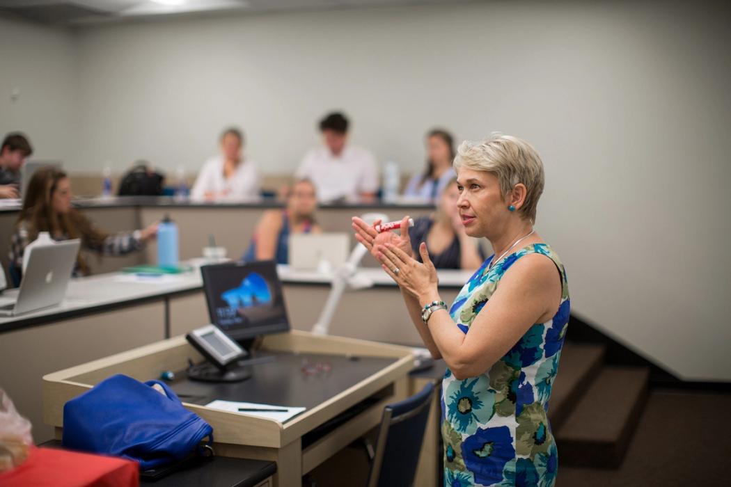 An economics professor lectures to a small class of students.