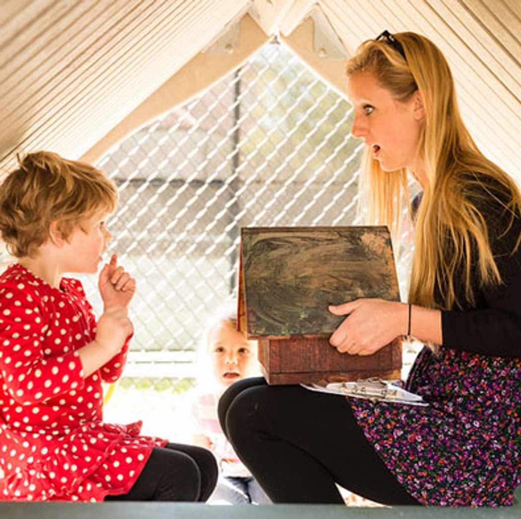 Rollins student and pre-school child play in a fort together.