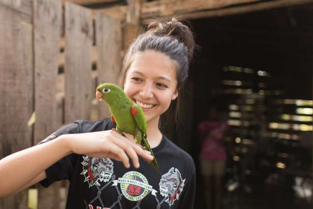 A student holding a green parakeet during a Dominican Republic field study.