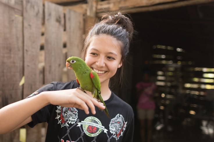 A Rollins student holds a parrot while on a study abroad trip the Dominican Republic.
