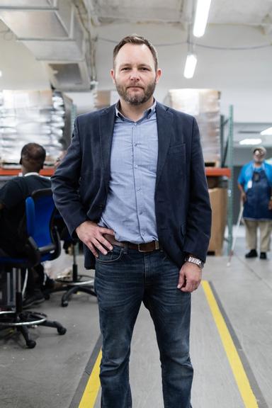 A portrait of Kyle Johnson standing in the Lighthouse Central Florida warehouse.