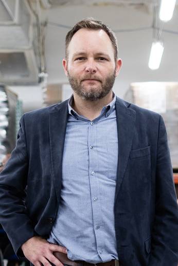 A portrait of Kyle Johnson standing in the Lighthouse Central Florida warehouse.
