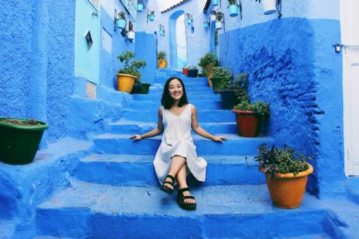 A study abroad student poses for a picture on a bright blue staircase in Morocco.