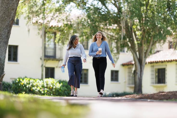 A female student walks across campus with a Rollins employee. 