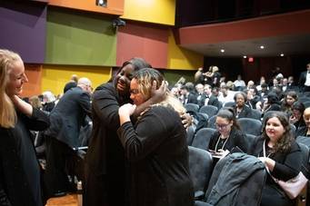 Rollins students prepare to perform, hugging.