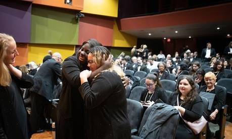 Rollins students prepare to perform, hugging.