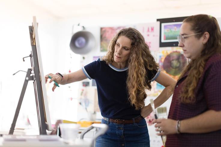 Studio art professor Dana Hargrove works on painting techniques with her student.