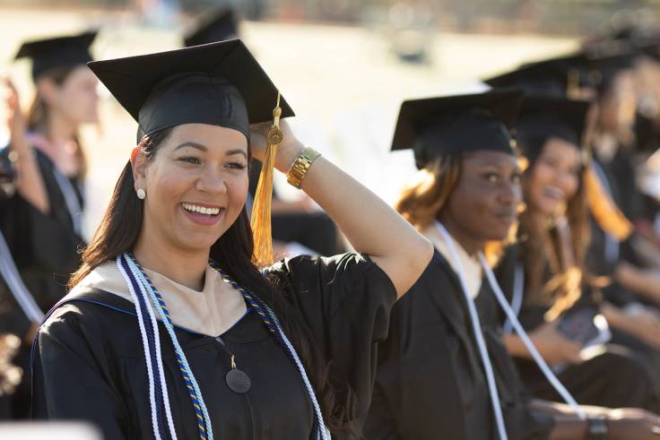 A Rollins college graduate smiles during a commencement ceremony.