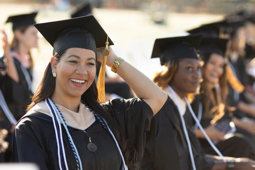 Adult graduate in cap and gown smiling.